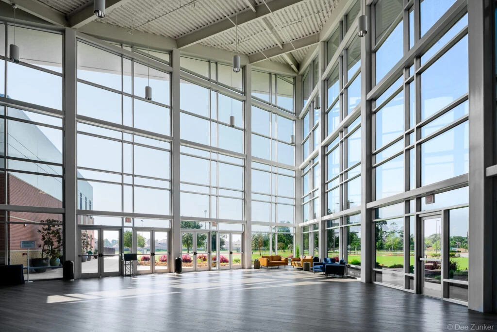 Soaring glass curtain wall atrium of a Houston church interior flooded with natural light and modern seating