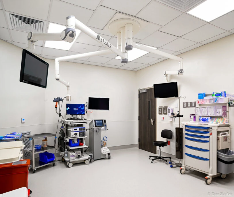 Fully equipped surgical suite with STERIS overhead lights, multiple monitors, medical supply carts, and endoscopy equipment in a Houston hospital.