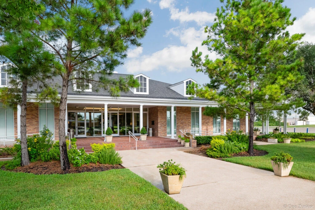 Brick exterior entrance of a church facility in Katy TX featuring a covered portico pine trees and manicured landscaping