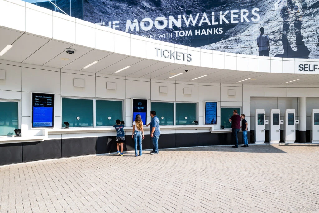 Modern ticket counter at Space Center Houston featuring self-service kiosks, digital displays, and visitors purchasing admission tickets