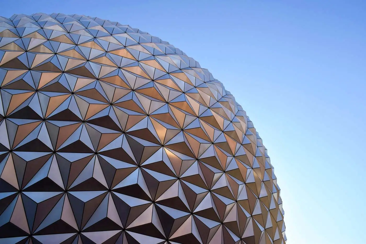 Geometric metallic sphere with triangular panels, luxury Swiss GuestLee rental design gleaming under a clear blue sky. | GuestLee luxury rental Switzerland