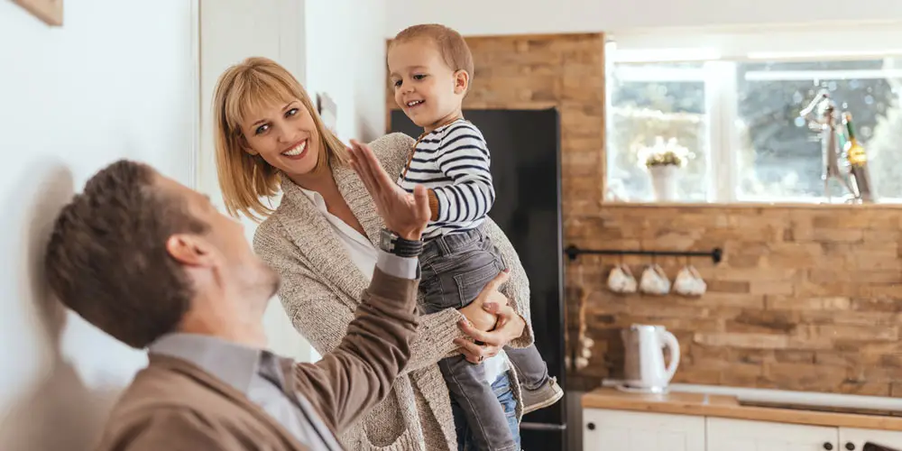 LEE_About_3 Family enjoys quality time in a luxurious GuestLee Swiss rental kitchen with wooden accents and natural light. | GuestLee luxury rental Switzerland