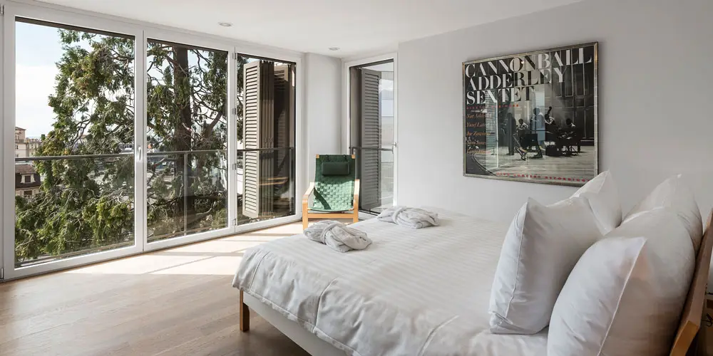 LEE_Buy_1 Luxurious Verbier chalet bedroom with double bed, designer decor, large windows, forest views—ideal for GuestLee rentals. | GuestLee luxury rental Switzerland