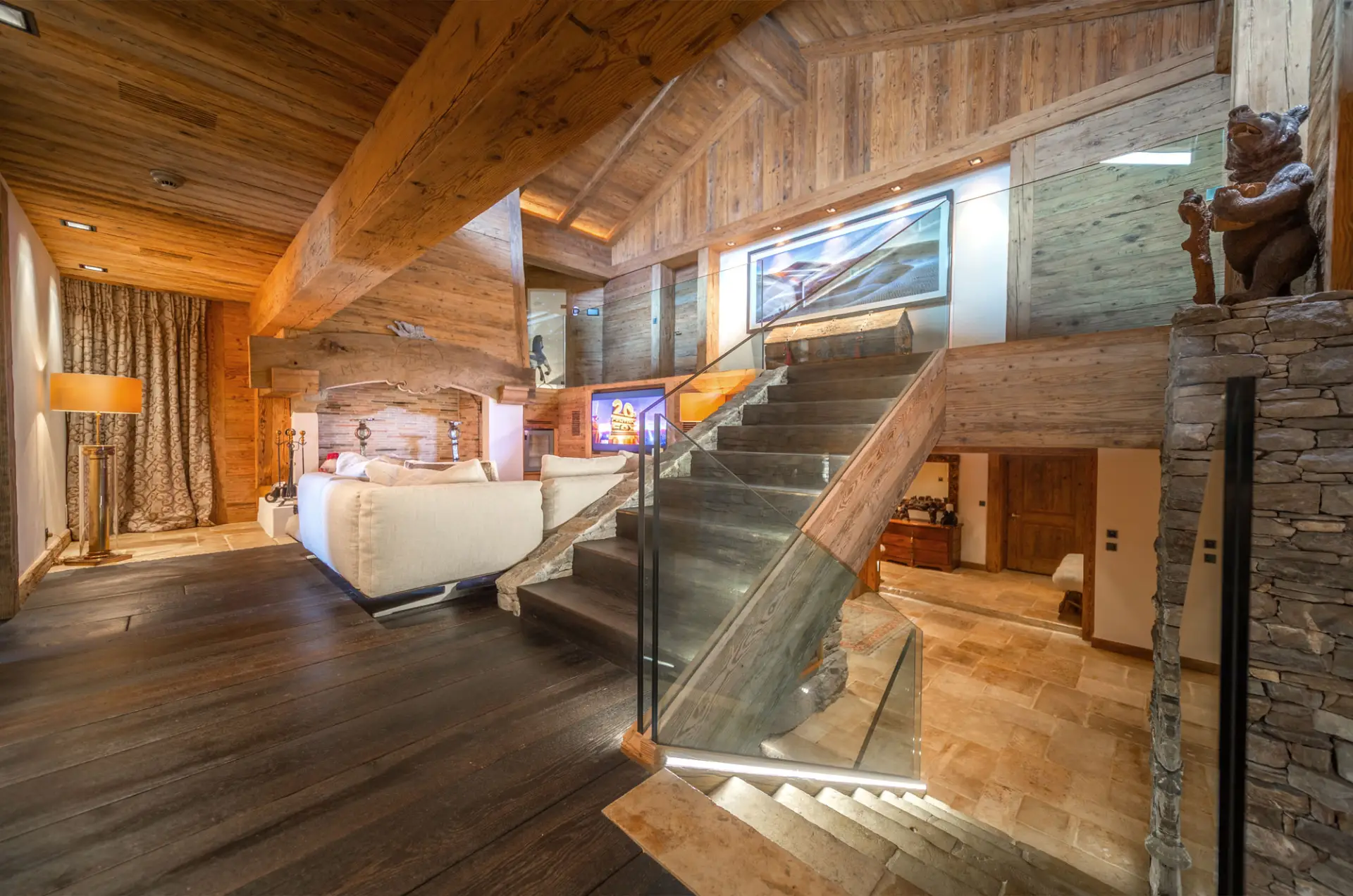 Luxury Verbier chalet rental: wood interiors, glass staircase, stone details, white sofa, warm lights&mdash;perfect Swiss getaway. | GuestLee luxury rental Switzerland