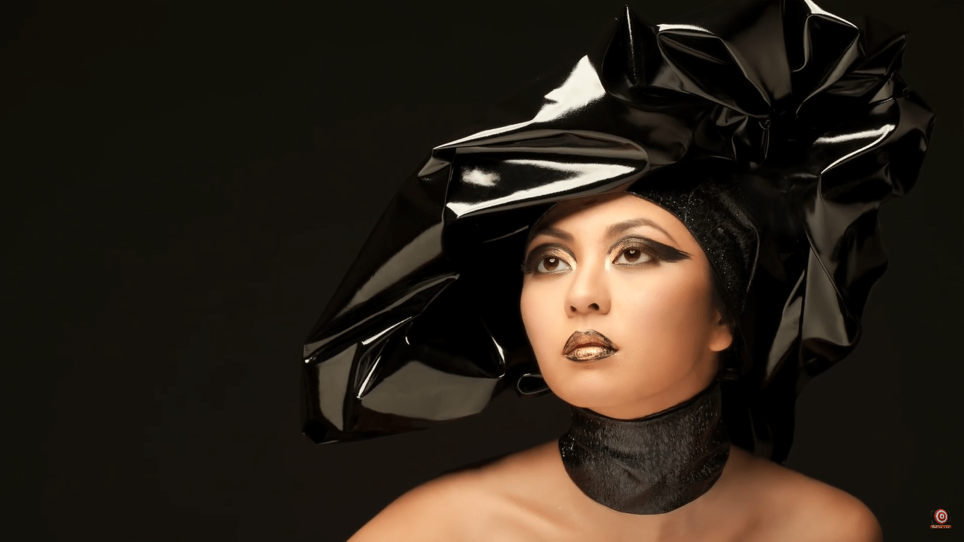 model with gold lipstick and eyeshadow wearing black vinyl hat