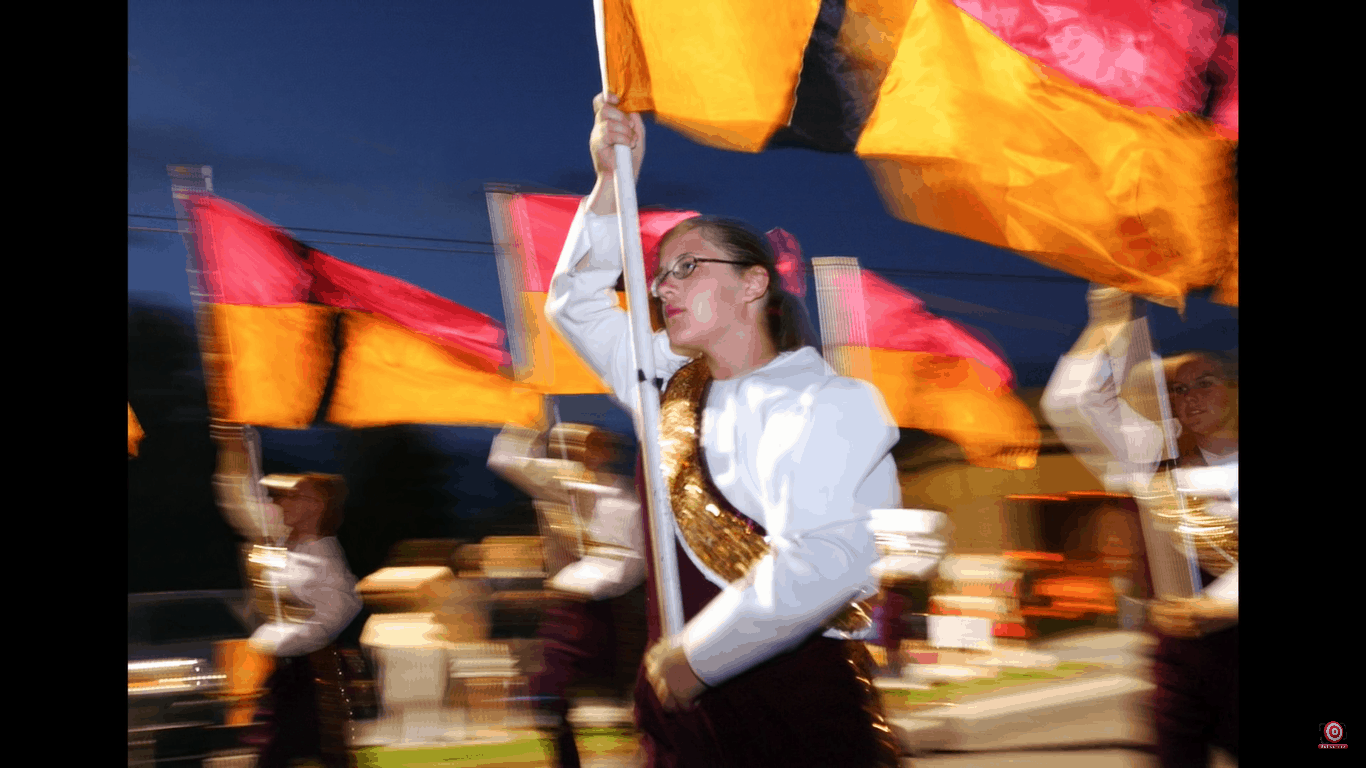 colorguard girl marching with flag, shot with shutter drag
