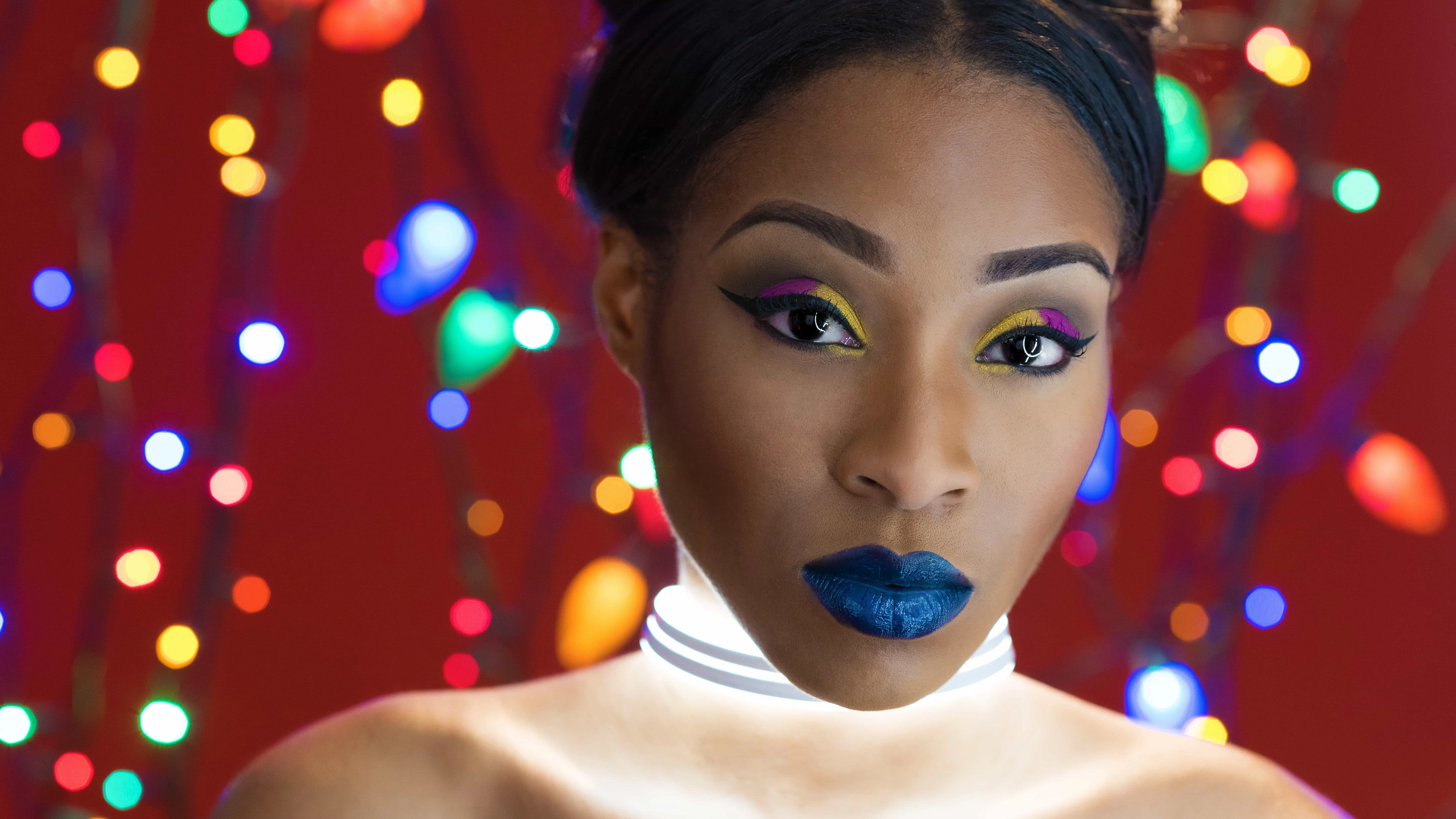 Fifth of DIY Christmas light portraits with Monae with light around neck, colored christmas lights and orange background