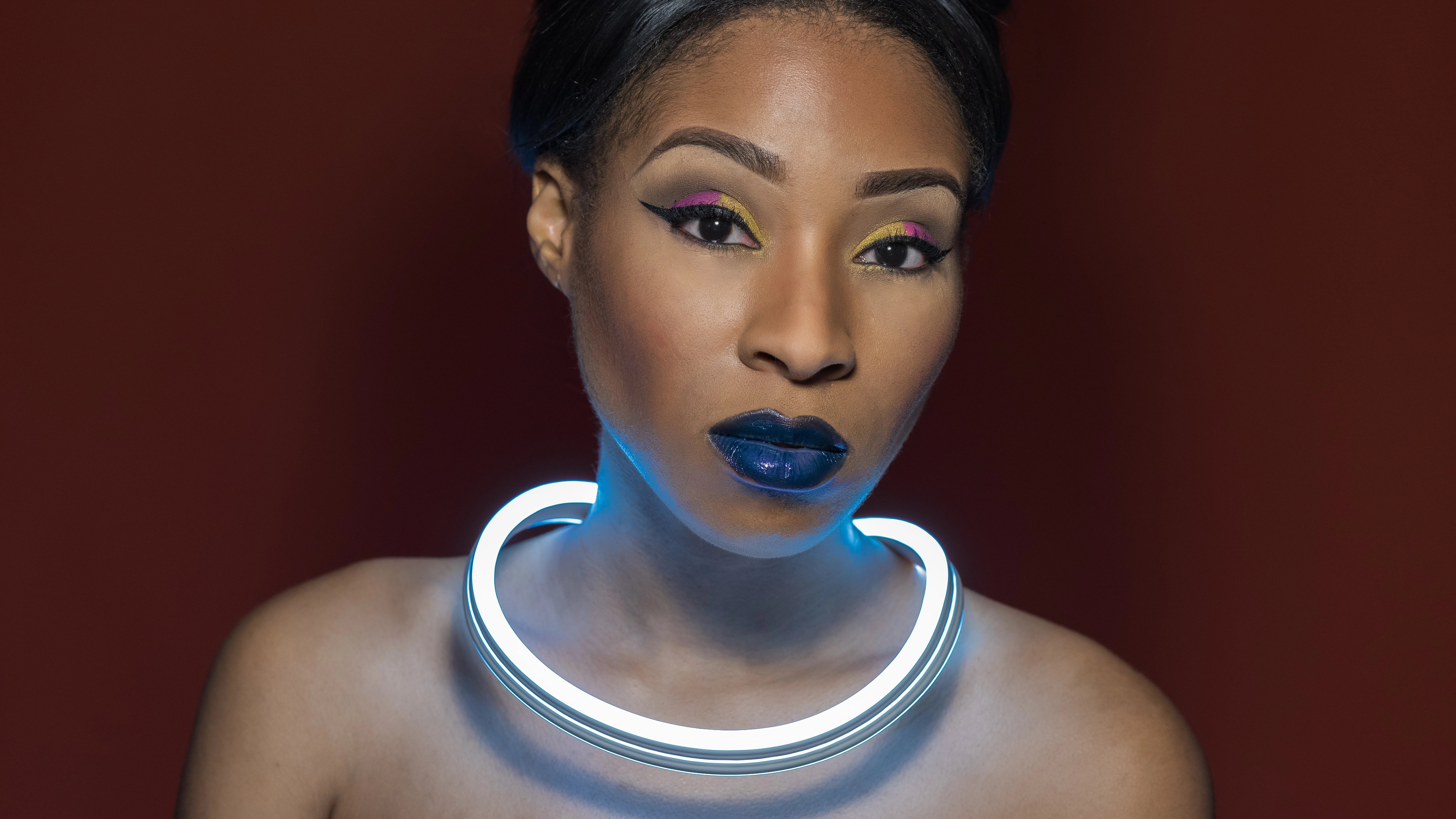 Monae with LED light around neck and orange background, no Christmas lights in background