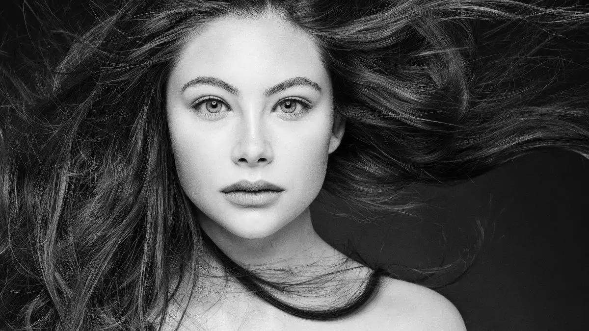 A black and white portrait captures the essence of success as a photographer, with the subject's long hair flowing around their face, looking directly at the camera.