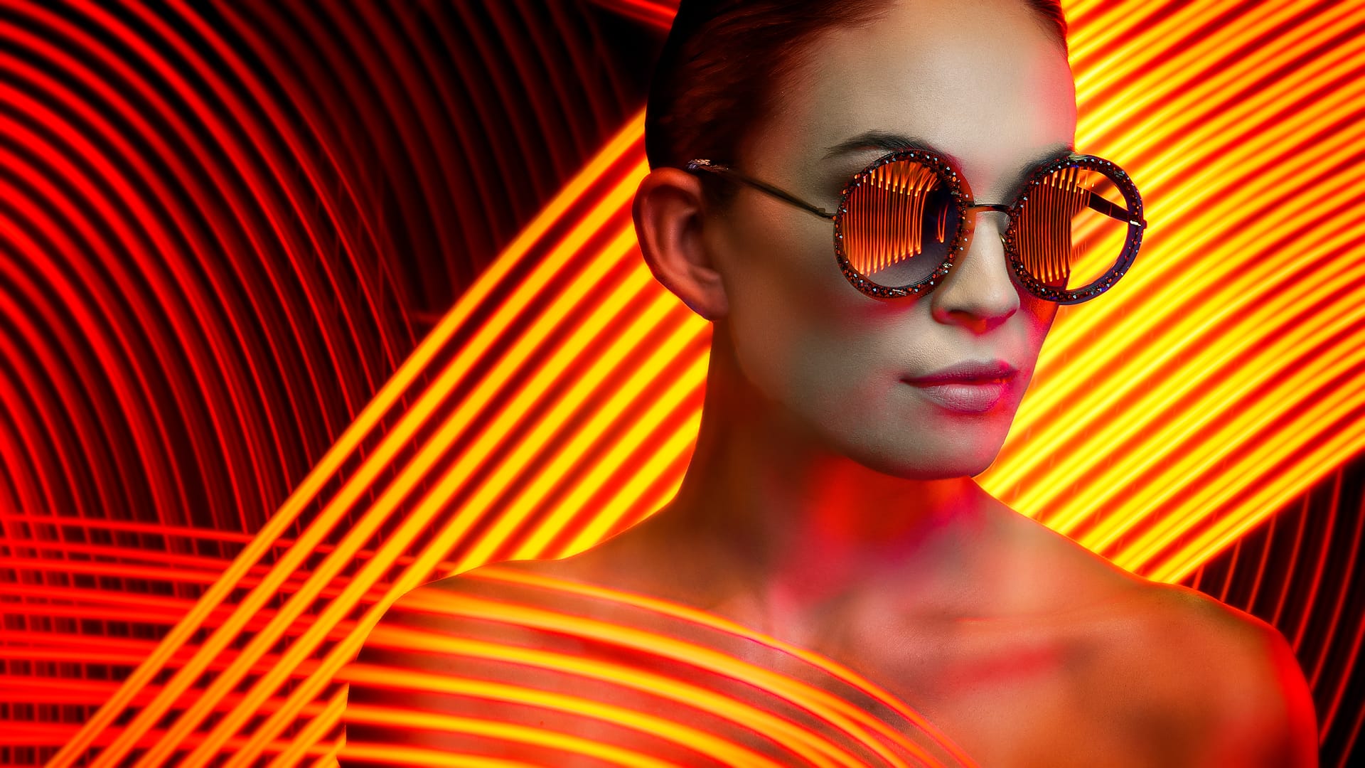 A Live Composite fashion portrait of a Person wearing reflective sunglasses against a dynamic background of red and orange light streaks.
