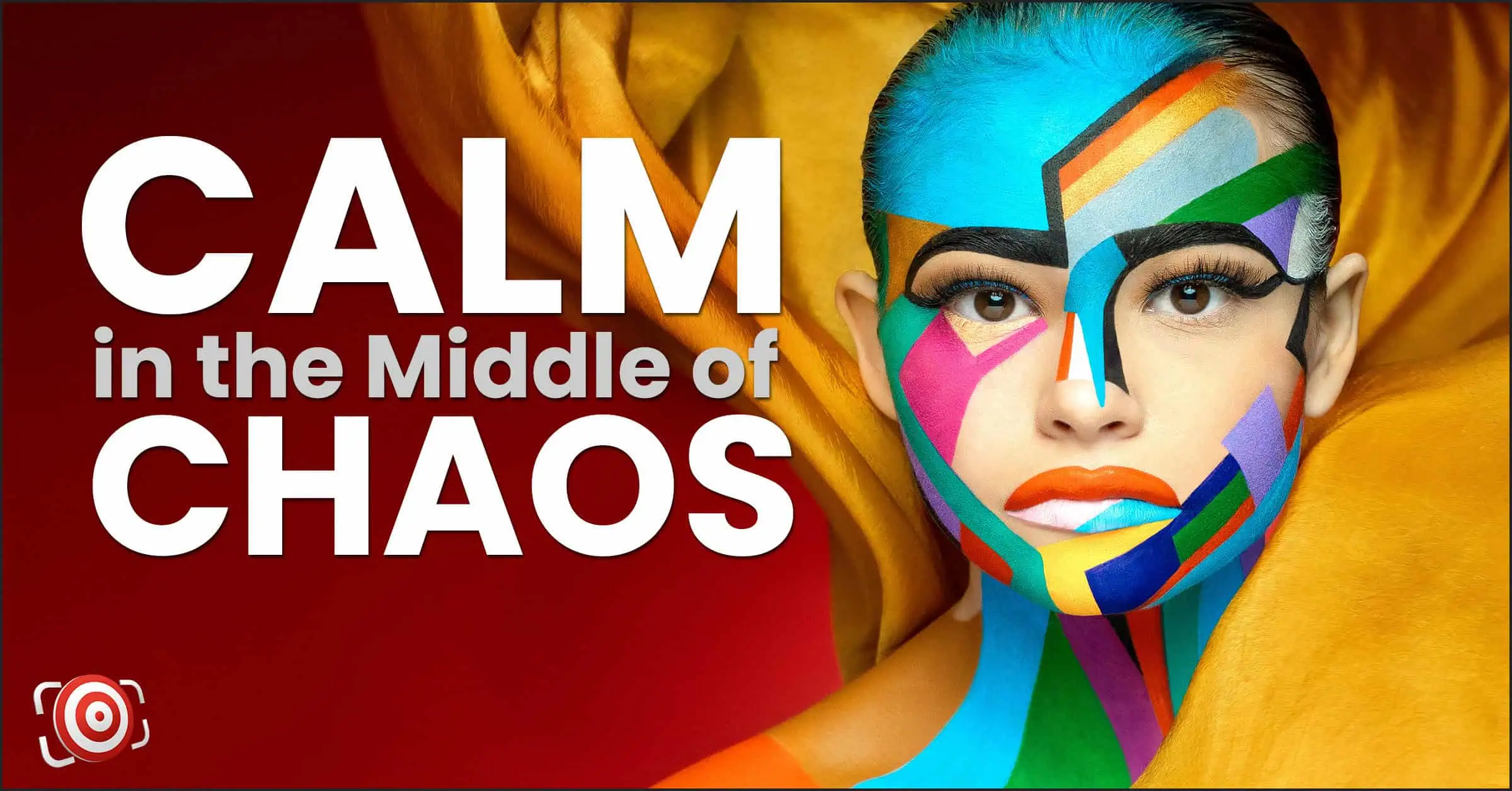A person with colorful geometric face paint stands against a red background, exuding calm in the middle of chaos. This striking fashion portrait captures serenity amidst vibrant hues, blending art and tranquility seamlessly.