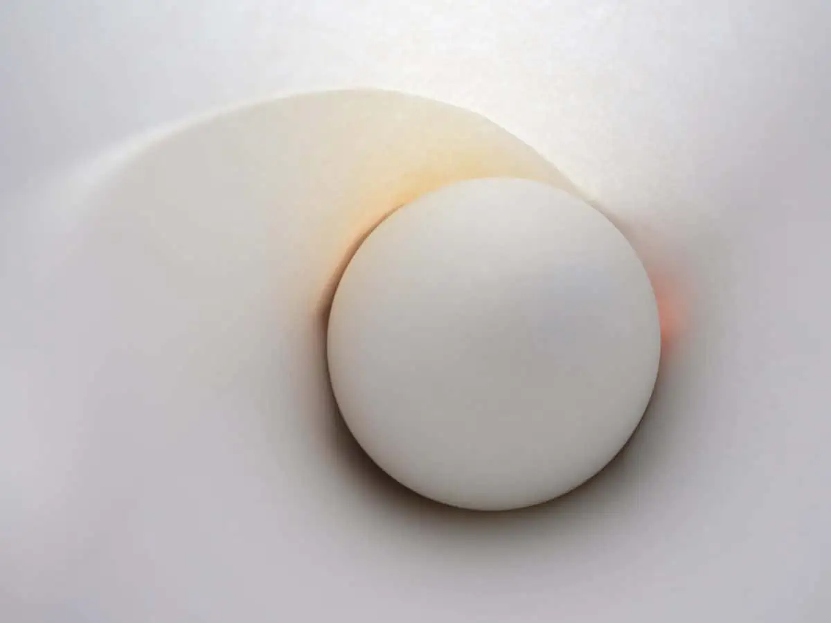 A white egg is sitting inside of a white paper.
