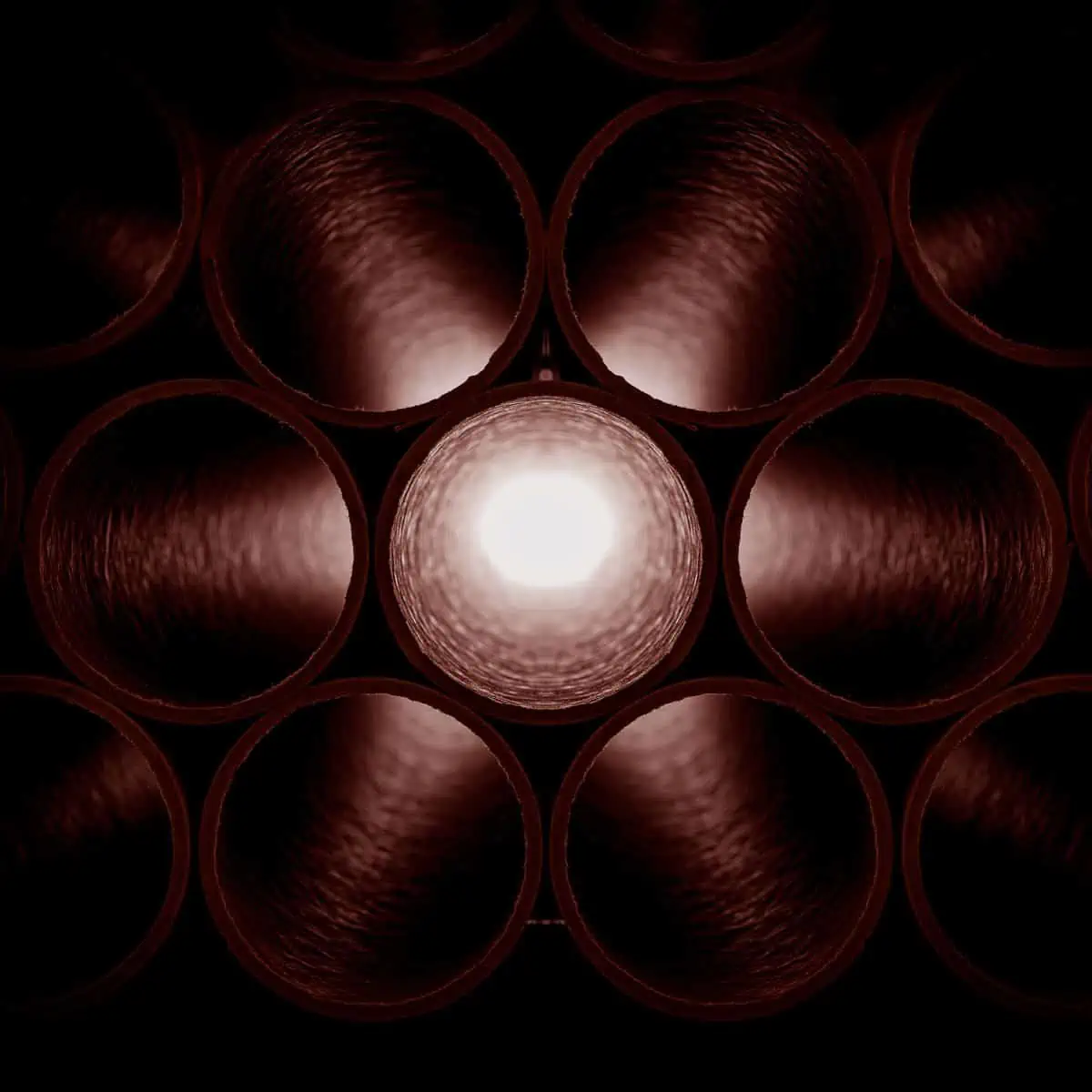 A dark background with a light shining through the pipes.