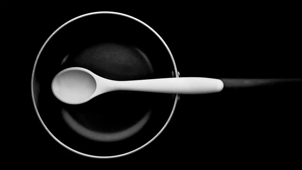 A black and white photo of a spoon in a pan.