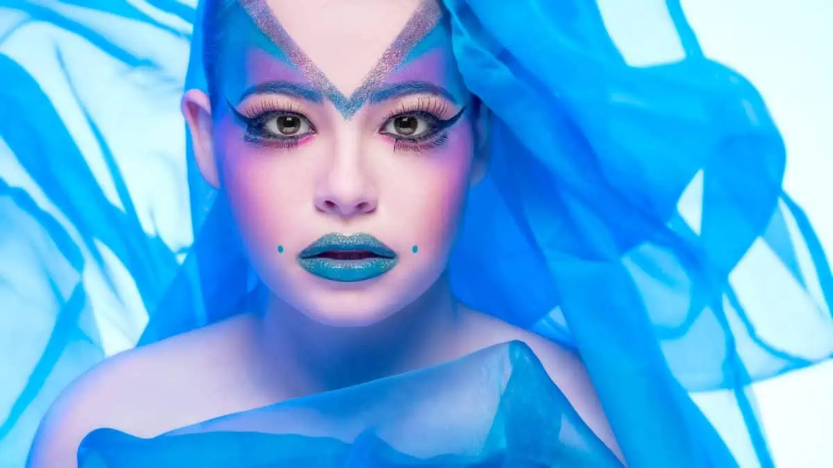 A woman with blue makeup and a blue veil.