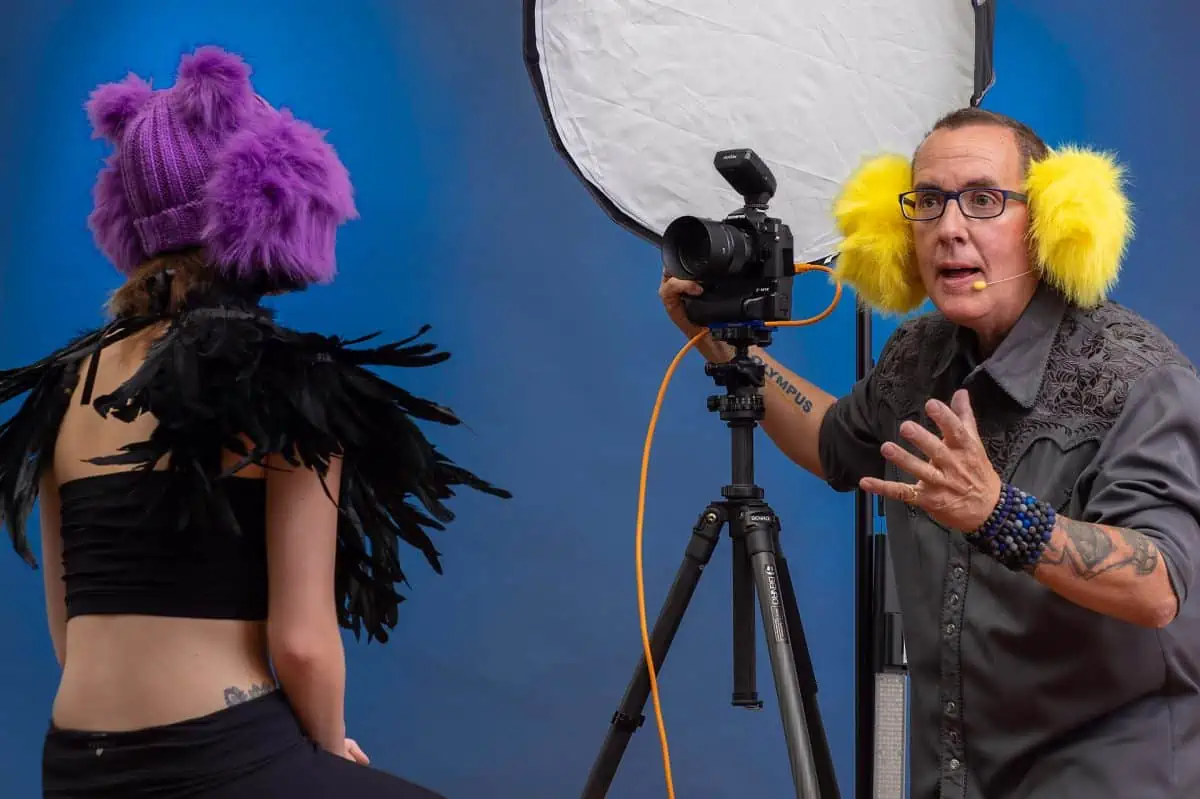 A man is taking a picture of a woman in a purple hat.