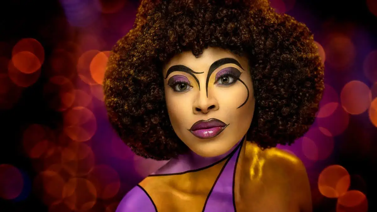 A woman with an afro and purple makeup.