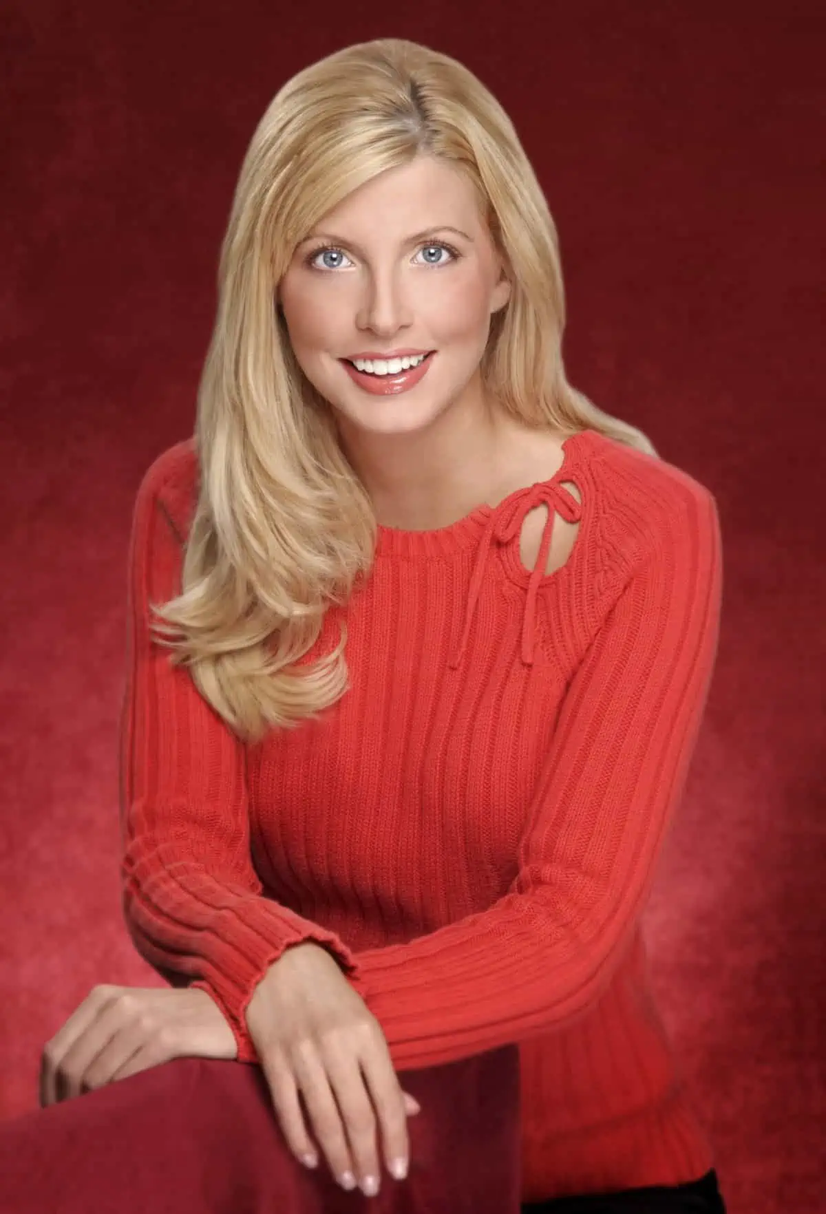 A blond woman in a red sweater posing for a photo.