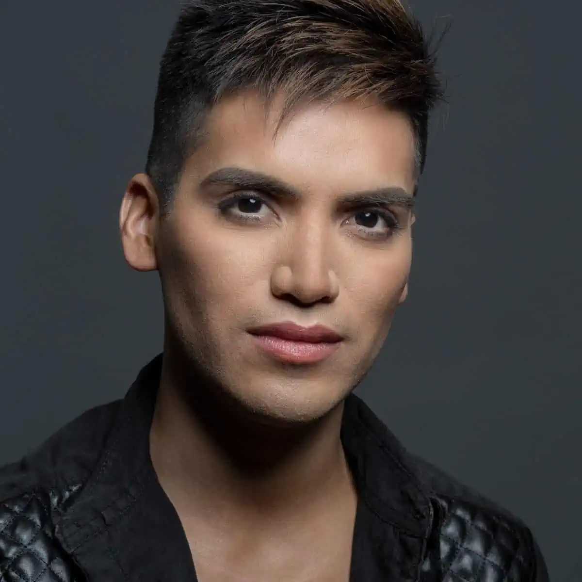 A man in a black leather jacket posing for a photo.