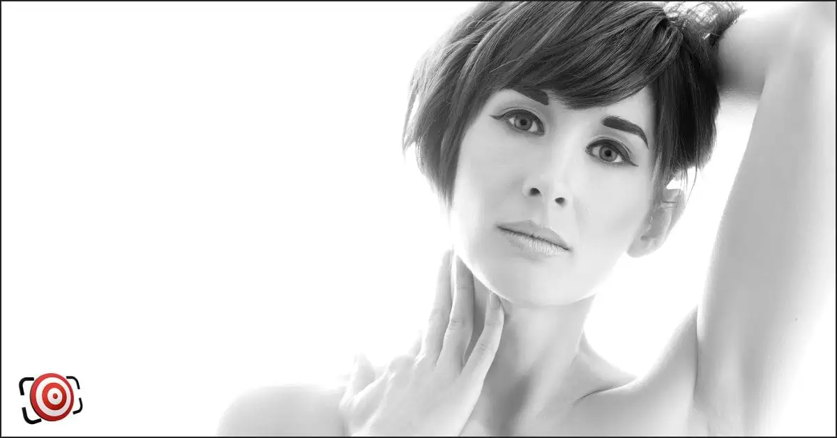 A black and white photo capturing the beauty of a woman's pose, illuminated with backlit lighting.