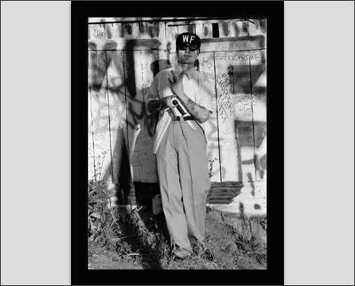 A black and white photo of a man standing in front of a wall.