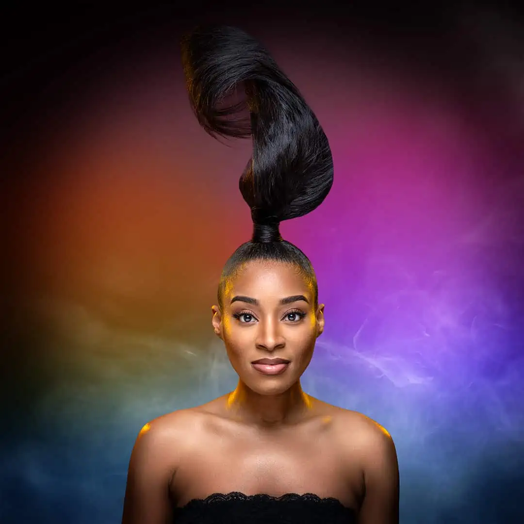 A beautiful black woman with long hair in a stunning black dress, exuding elegance and confidence, posing gracefully in front of a vibrant and captivating colorful background.
