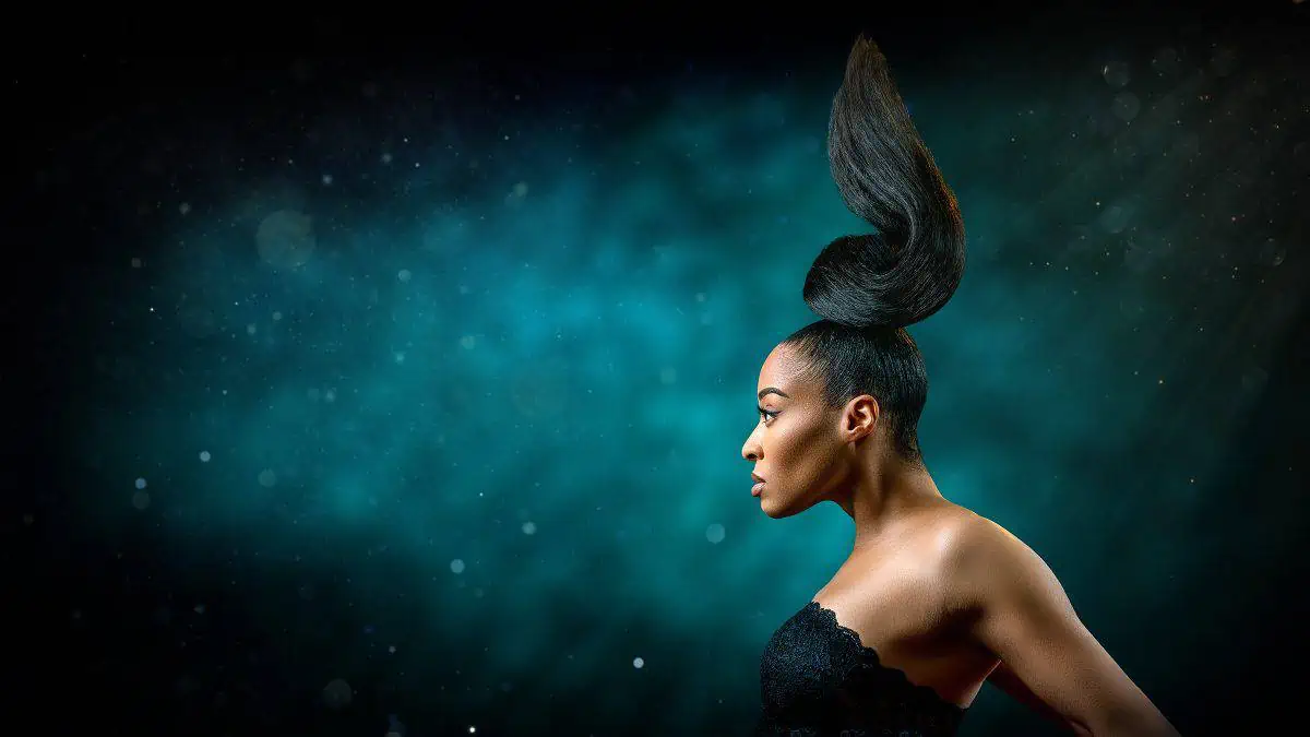A woman with long hair standing in front of a dark background.