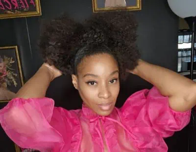 A black woman in a pink top posing for a colorful beauty portrait.