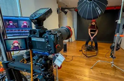 A creative woman is sitting in front of a camera in a studio, capturing her beauty through a captivating portrait.