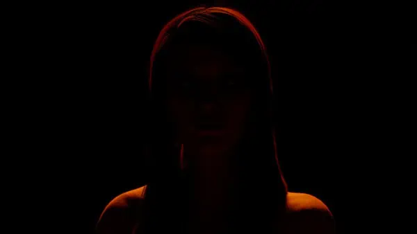A creative beauty portrait features a woman's face beautifully showcased in the dark.
