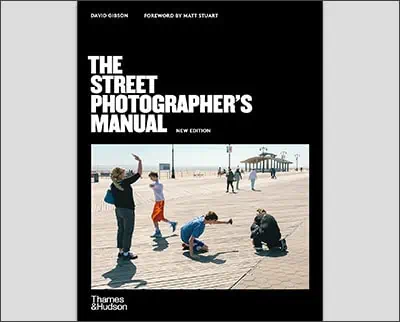 Cover of "the street photographer's manual" book, featuring a group of people interacting on a boardwalk with one person taking a photograph by Lindsay Adler.