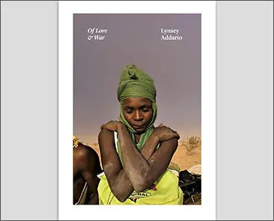 A book cover featuring a photograph of a woman in a green headwrap and yellow garment sitting in a contemplative pose against a dusky sky, with the title "of love & war" by Lindsay