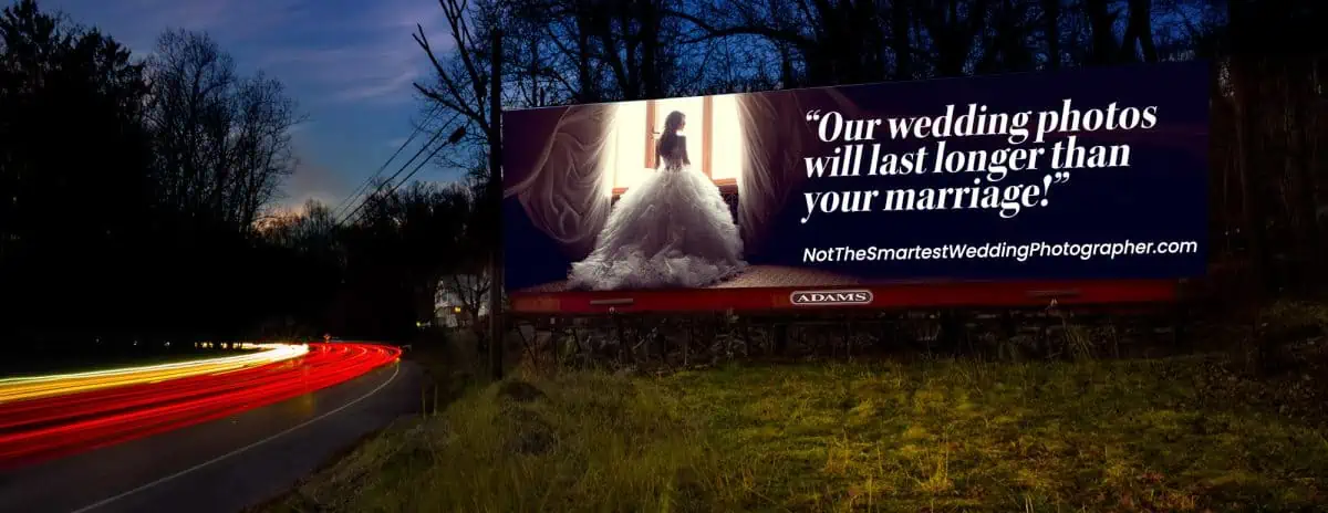 Billboard with a bold wedding photography advertisement at dusk, featuring a car's light trails on the road.