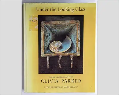 A book titled "Under the Looking Glass" featuring color photographs by Olivia Parker with an introduction by Mark Strand and Kyle Cassidy.
