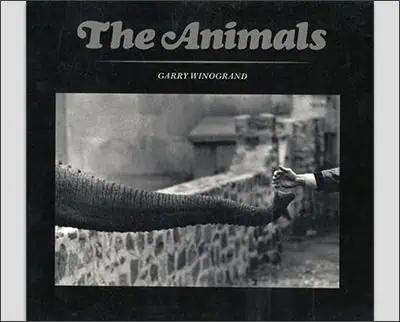 Cover of the book "the animals" by garry winogrand, featuring a black and white photo of a human hand and an elephant trunk reaching towards each other.