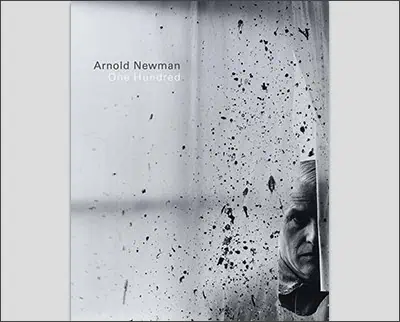 Cover of a book titled "Arnold Newman: One Hundred," featuring a black-and-white photograph reminiscent of works by Margaret Bourke-White, with a man's partially visible face behind textured glass.