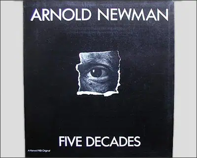 A cover of a book titled "Arnold Newman: Five Decades" featuring a close-up of an eye peering through a torn hole in a black background, reminiscent of the striking photographic style of Margaret Bourke-White.