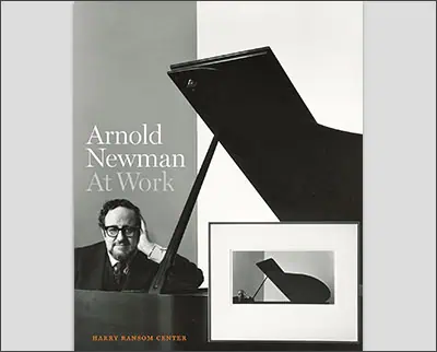 Cover of the book "Arnold Newman At Work" by Harry Ransom Center, depicting a man resting his head on his hand beside a grand piano and a framed photograph of Margaret Bourke-White.