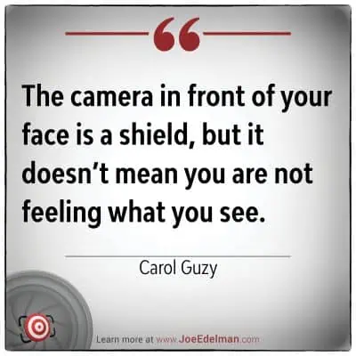 Image quote: "The camera in front of your face is a shield, but it doesn’t mean you are not feeling what you see." - Carol Guzy, whose Pulitzer-winning photojournalism excellence captures profound emotions beyond the lens.