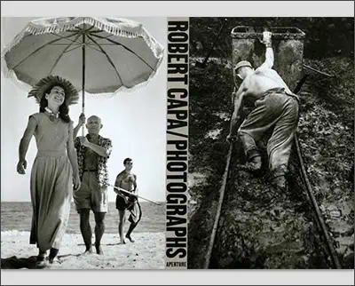 Book cover featuring a split image: a beach scene on the left with people walking under an umbrella and a black-and-white photo of legendary war photographer Robert Capa descending tracks on the right. Title reads "Robert Capa/Photographs.