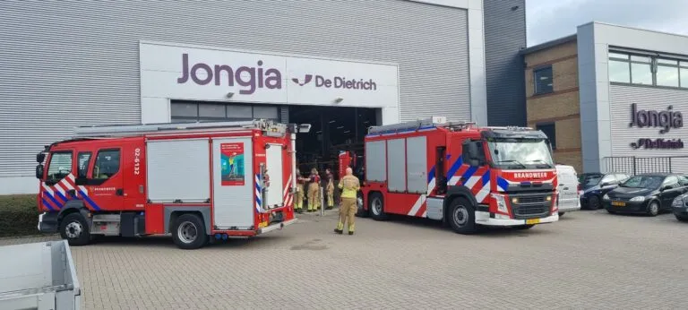 Two fire engines parked outside the Jongia De Dietrich building during Safety Day, with firefighters walking into the production hall.