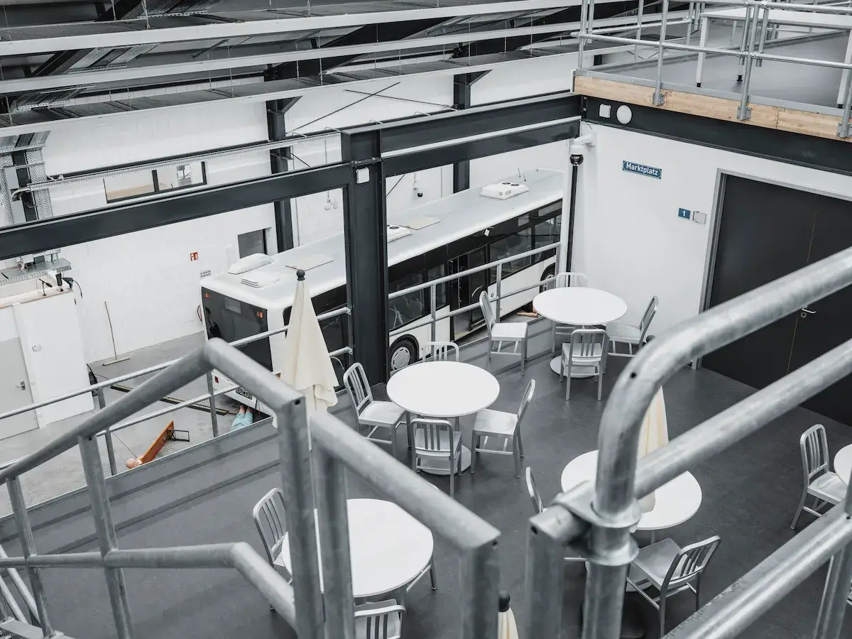 An overhead view of a large-scale simulation facility featuring a cafe-style training area and a full-sized bus for integrated in-situ emergency response drills.