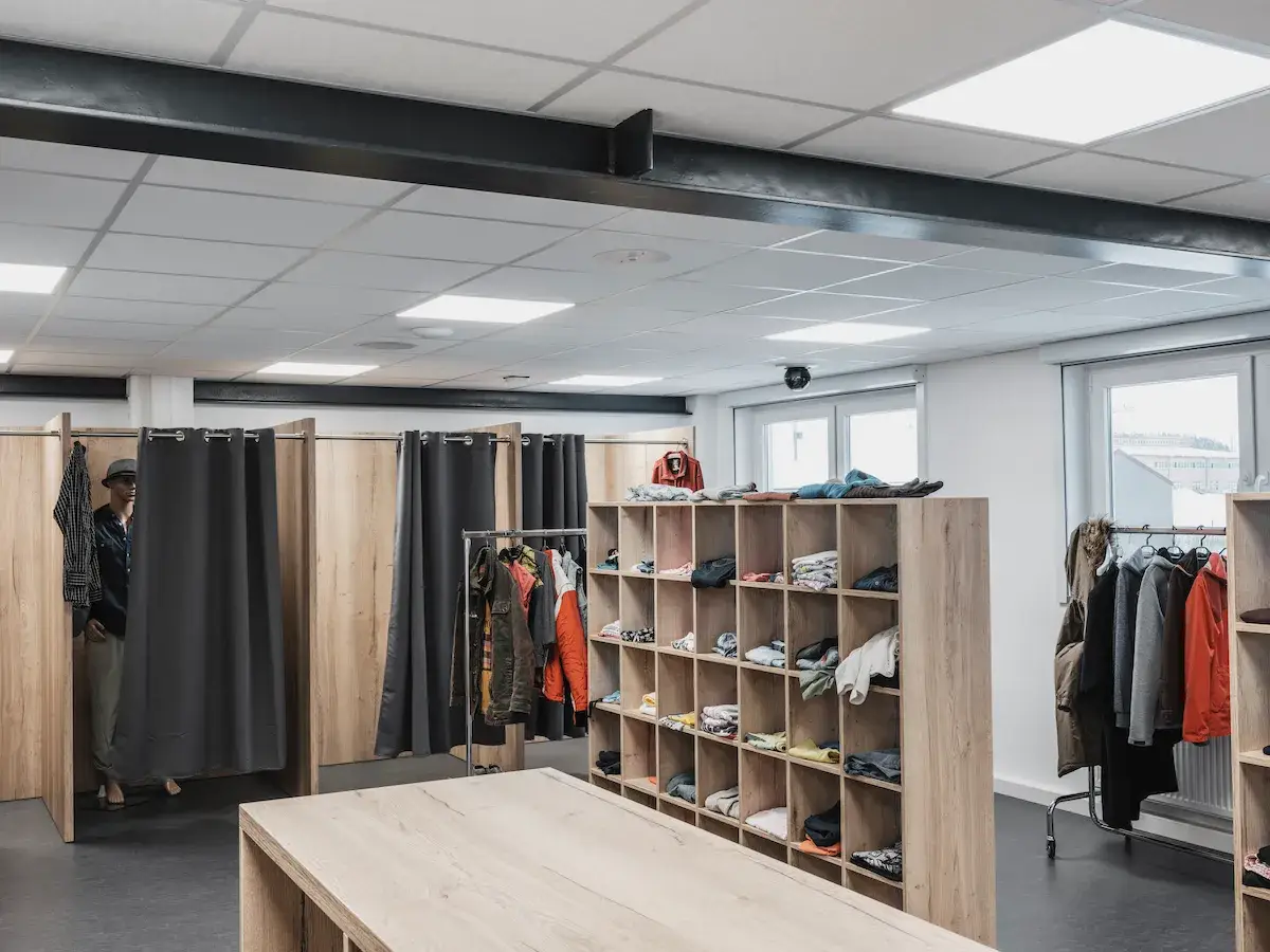 A realistic retail simulation room featuring clothing racks, dressing rooms, and manikins used for behavioral analysis and public safety training.