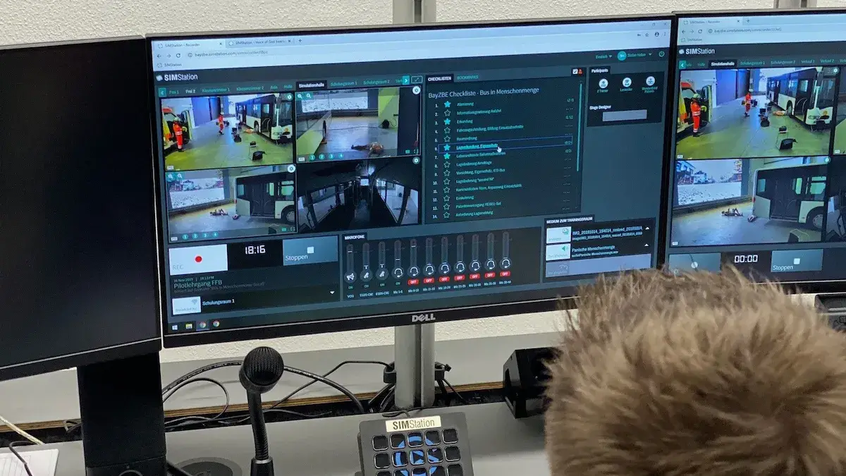 Close-up of a monitor running SIMStation recording software, showcasing a multi-view camera layout of a bus simulation alongside a digital performance assessment checklist for real-time evaluation.