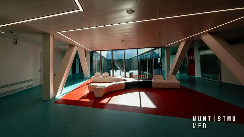 SIMU Brno Simulation Centre interior: modern lounge with white modular seating on a red carpet and glass walls.