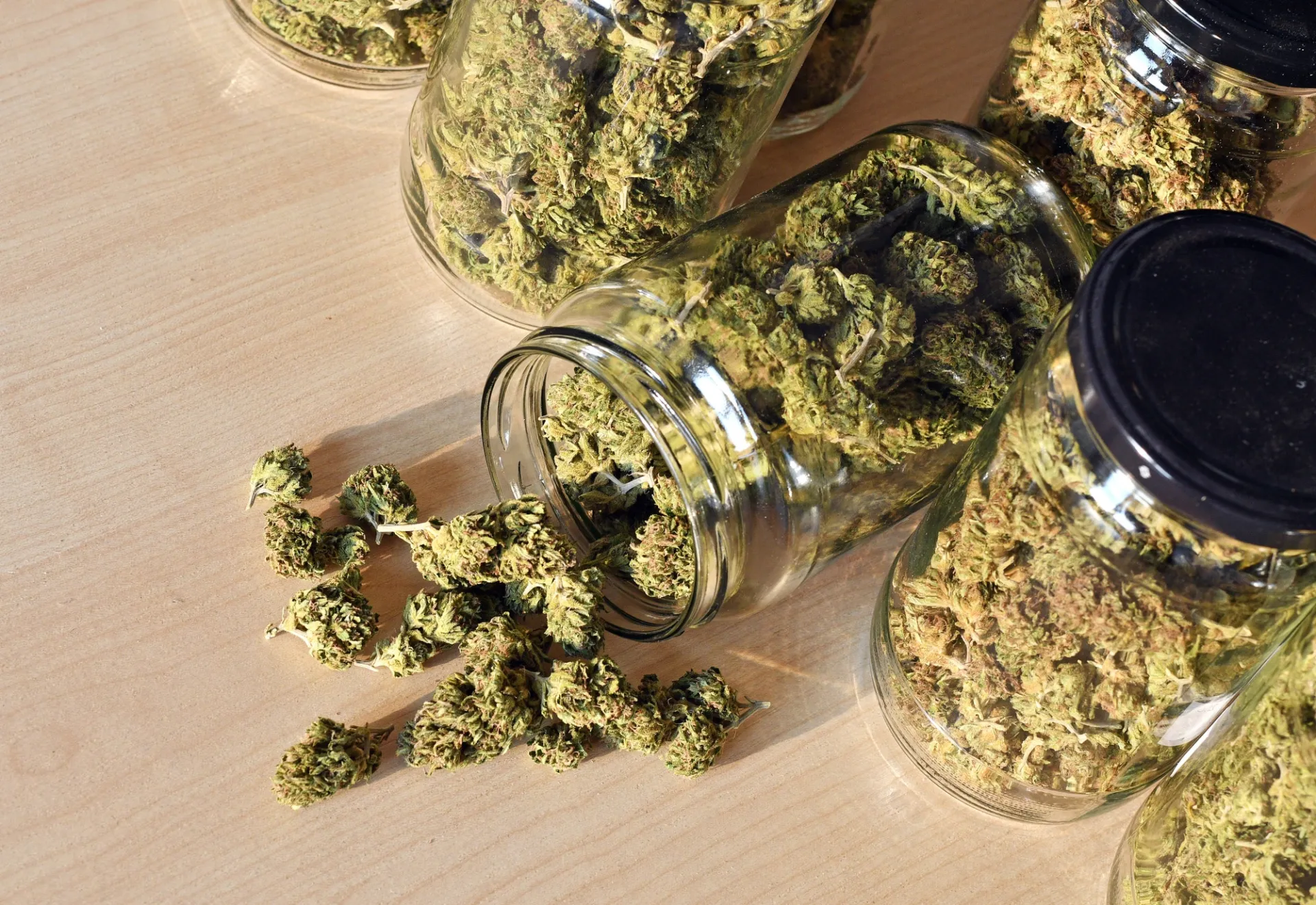 A group of jars filled with marijuana sitting on top of a wooden table