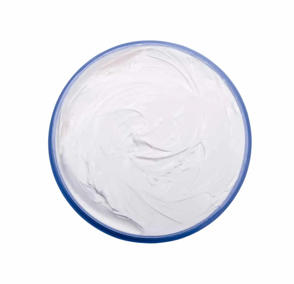 Opened plastic container with cream on a white background