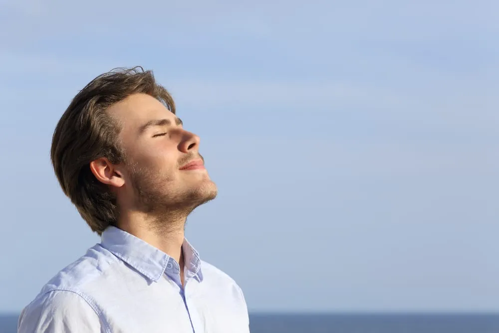 Happy young man breathing deep with the horizon in the background