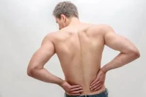 Young man stand and hold hands on back. He feels pain in kidneys area. Isolated on white background
