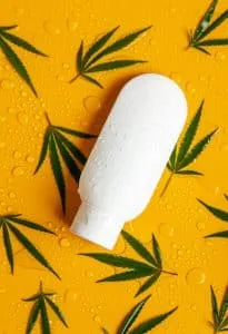 Cosmetics with cannabis extract on a wet background. Selective focus.